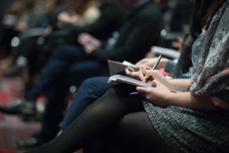 selective focus photography of people sitting on chairs while writing on notebooks by The Climate Reality Project courtesy of Unsplash.