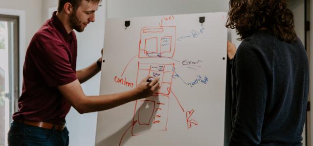 man drawing on dry-erase board by Kaleidico courtesy of Unsplash.